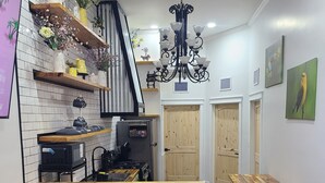 Een keuken met een houten aanrecht, zwarte stoelen, een zwarte prullenbak en een kroonluchter.