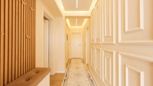 A hallway with a bench, wooden paneling, and a patterned carpet. - Villa Royale in Durr s (Durrës)