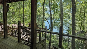 Eine Holzterrasse mit Geländer, die auf einen See mit Bäumen blickt.