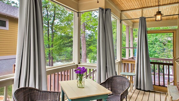 Eine überdachte Veranda mit Tisch, Stühlen und einem Blumenstrauß.