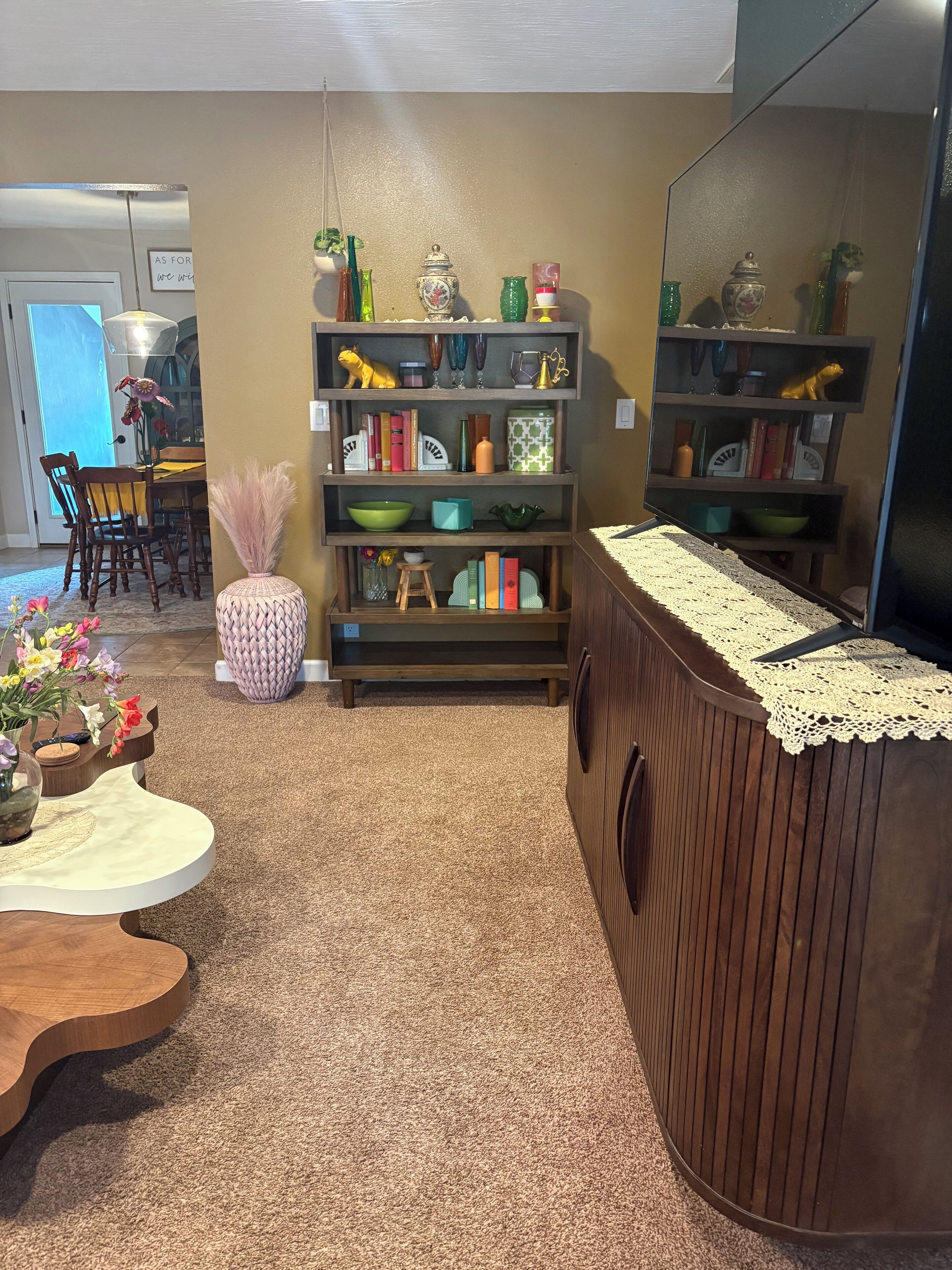 A living room with a wooden coffee table, a bookshelf, and a large mirror.