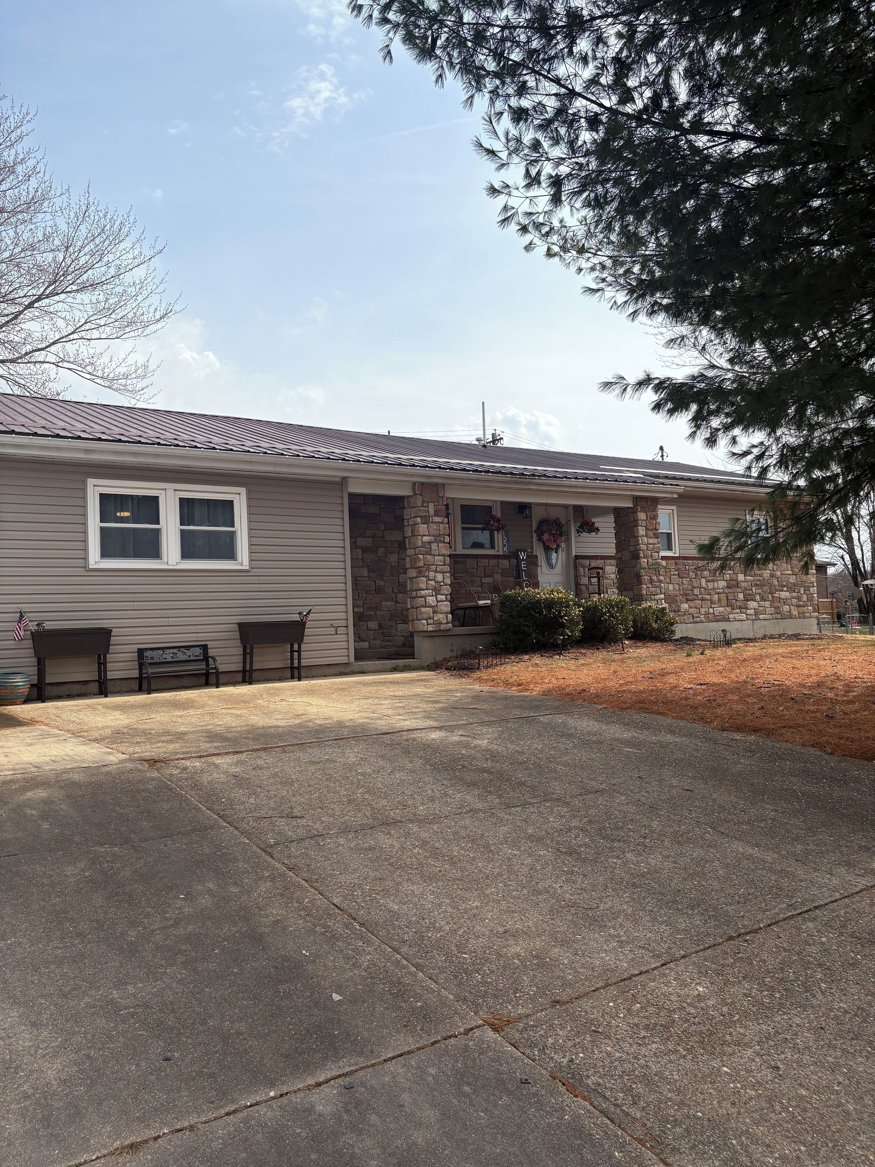 A residential house with a stone entrance, a front porch with a bench, and a clear sky.