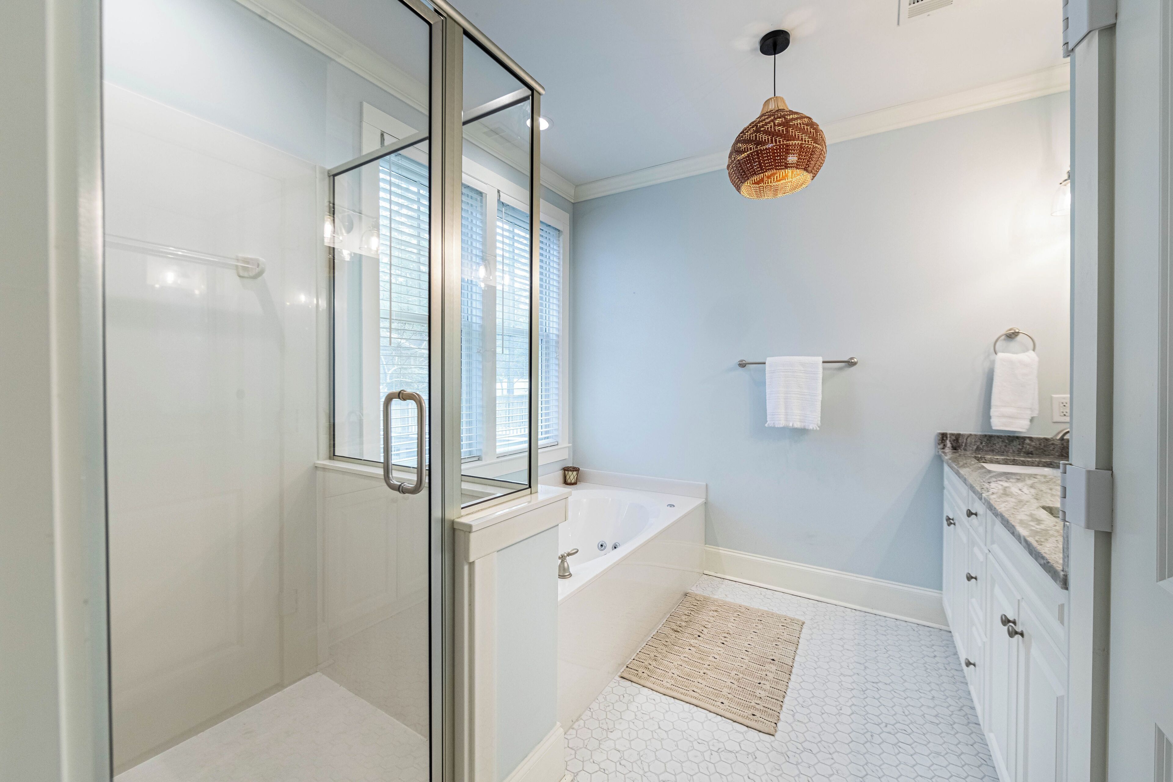 Une salle de bain moderne dotée d’une douche à parois de verre, d’une baignoire sur pieds et d’un meuble-lavabo avec un plan de travail en marbre.