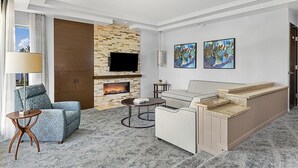 Una sala de estar moderna con chimenea de piedra, un televisor de pantalla plana, dos obras de arte, un sofá, una mesa de centro y una alfombra estampada.