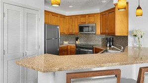 Una cocina con armarios de madera, un refrigerador de acero inoxidable, un microondas y una encimera de granito.