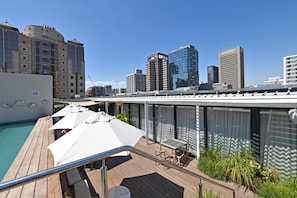 A rooftop terrace with a pool, outdoor seating, and city skyline views. - Trendy Lifestyle Building 1 Bedroom Secure (Cape Town)