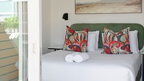 Quarto de hotel com cama, almofadas, um quadro na parede e janela com vista.