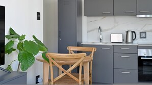 Uma cozinha moderna com armários cinzas, uma cadeira de madeira, um vaso com planta e uma torradeira.