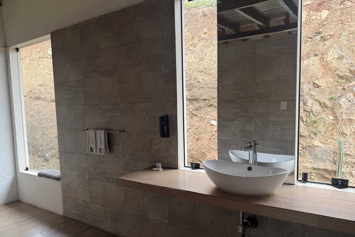 A modern bathroom with a large window, a vessel sink, and a towel rack.