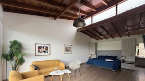 A room with a sofa, two chairs, a bed, a large plant, and artwork on the walls. - Ranch Pachacamac (Pachacamac)