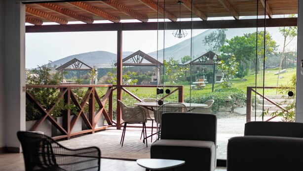 A covered outdoor seating area with a view of a mountainous landscape. - Ranch Pachacamac (Pachacamac)
