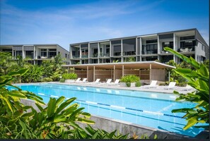 Un hôtel moderne doté d’une piscine, de chaises longues et d’un espace extérieur couvert.