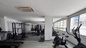A gym with cardio equipment, weight machines, and a mirrored wall. - LUXURY WATERFRONT BEDROOM with private bathroom and AC in Cielo Mar Cartagena (Cartagena de Indias)