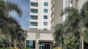 A modern building with a central entrance, surrounded by well-maintained greenery and palm trees. - LUXURY WATERFRONT BEDROOM with private bathroom and AC in Cielo Mar Cartagena (Cartagena de Indias)