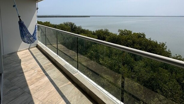A balcony with a view of the sea, a hammock, and a glass railing. - LUXURY WATERFRONT BEDROOM with private bathroom and AC in Cielo Mar Cartagena (Cartagena de Indias)