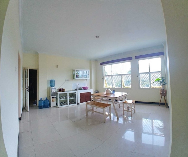 A spacious kitchen with a dining area, large windows, and a water dispenser.