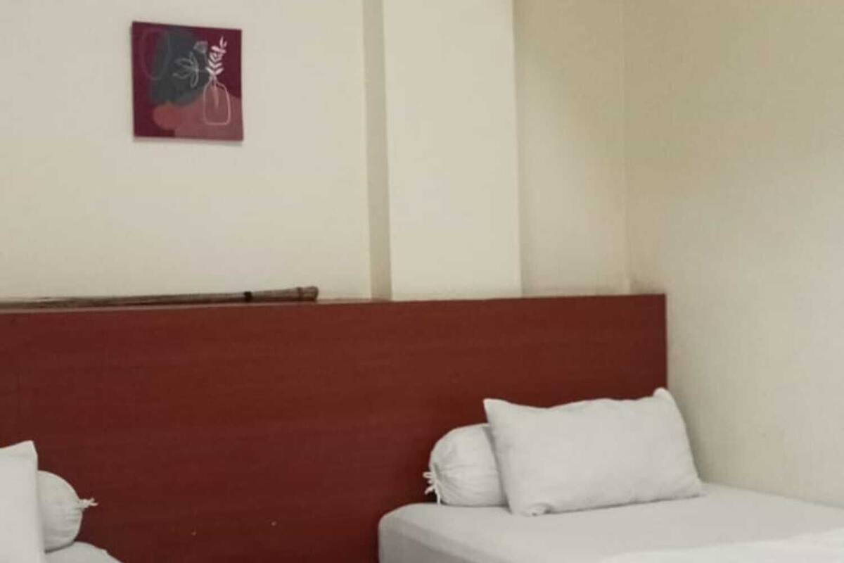 A hotel room with two beds, a red headboard, white bedding, and a small artwork on the wall.