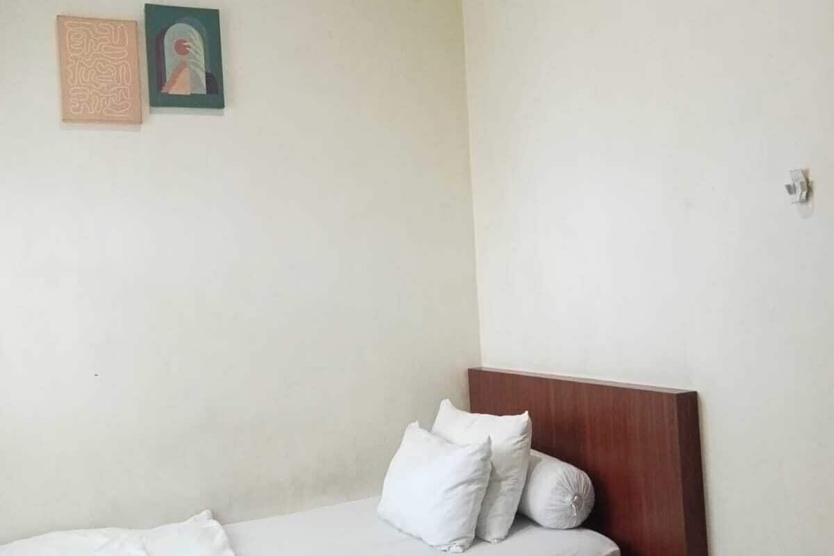 A bedroom with a single bed, a wooden headboard, and two wall-mounted pictures.