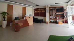 Una recepción con un cartel, un televisor y una planta en el vestíbulo de un hotel.