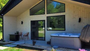 A modern house with a covered patio, a hot tub, and a garden with pebbles and plants.
