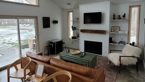 A modern living room with a fireplace, a television, and a view of the outdoors.