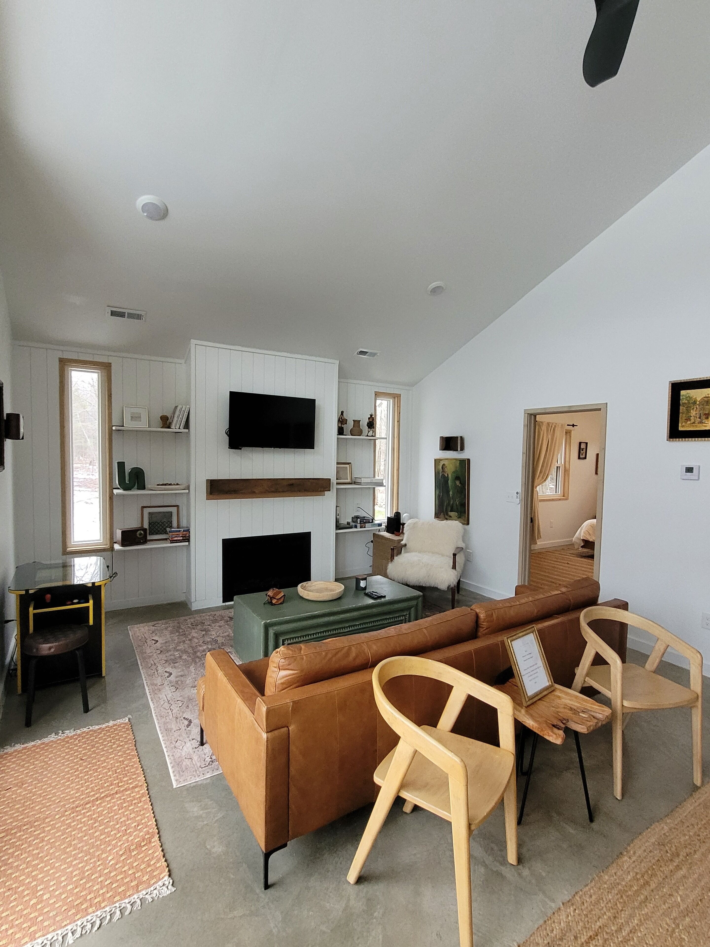 A modern living room with a sofa, chairs, a coffee table, a fireplace, and a television.