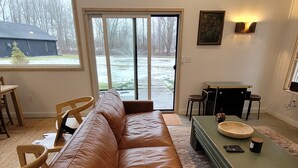 A spacious living room with a brown leather couch, a coffee table, and a dining table with chairs.