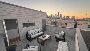 Une terrasse sur le toit aménagée avec un canapé, des fauteuils et une table basse.
