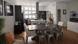 Une cuisine moderne dotée d’un îlot central, d’un coin repas avec des chaises et d’une grande fenêtre qui laisse entrer la lumière naturelle.