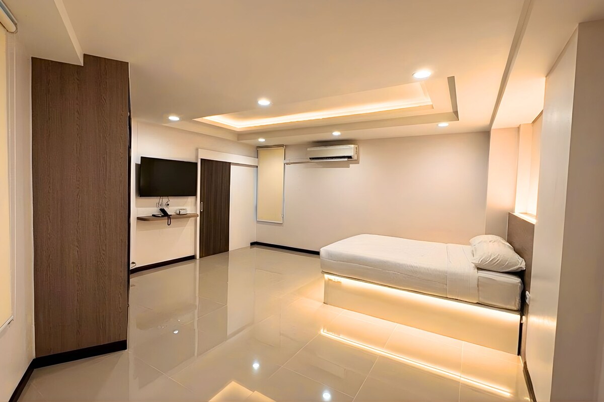 A modern bedroom with a bed, a TV, and an air conditioning unit.
