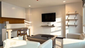 Un soggiorno moderno con una TV a schermo piatto, un tavolino da caffè in vetro e un divano.
