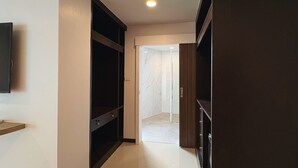 Un corridoio con un armadio in legno scuro, un pavimento piastrellato di bianco e un muro in marmo.