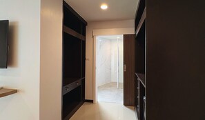 A hallway with a dark wooden wardrobe, a white tiled floor, and a marble wall. - Paul and Pam Hotel Bangkok (Bangkok)