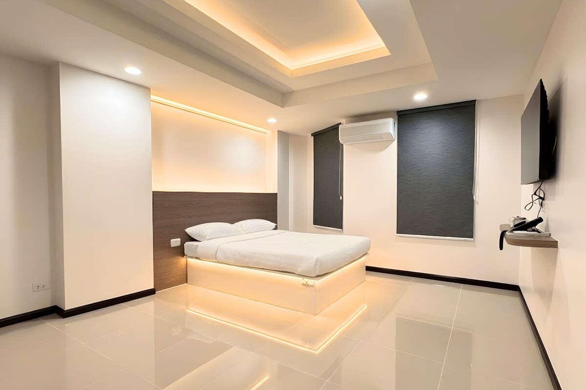A modern bedroom with a bed, a TV, and a window.