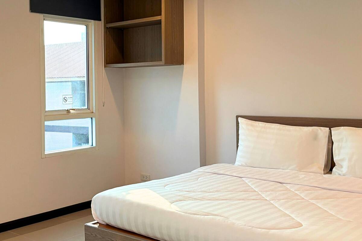 A bedroom with a bed, a window, and a built-in shelf.