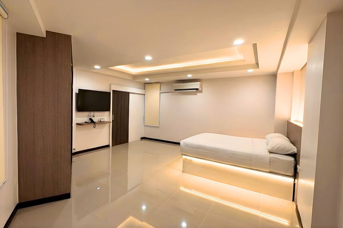 A modern bedroom with a bed, a TV, and an air conditioning unit.