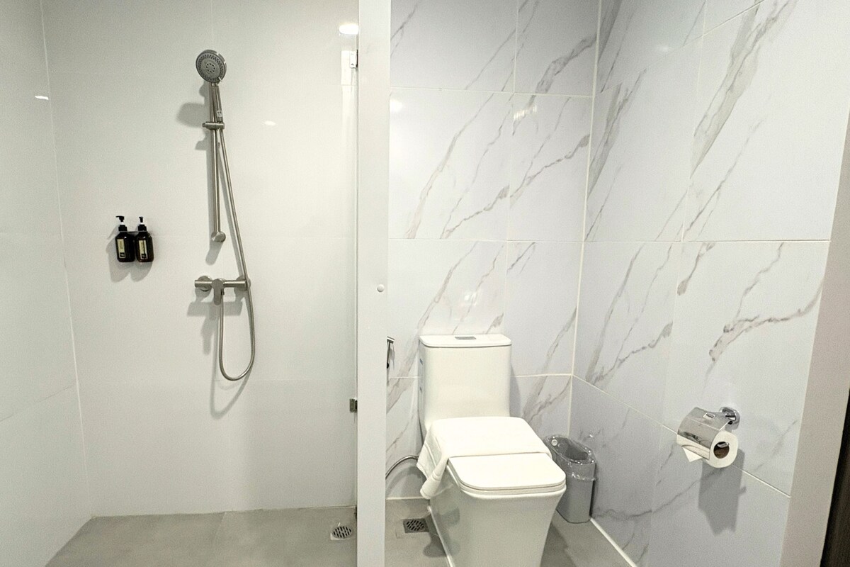 A bathroom with a shower, toilet, and marble walls.