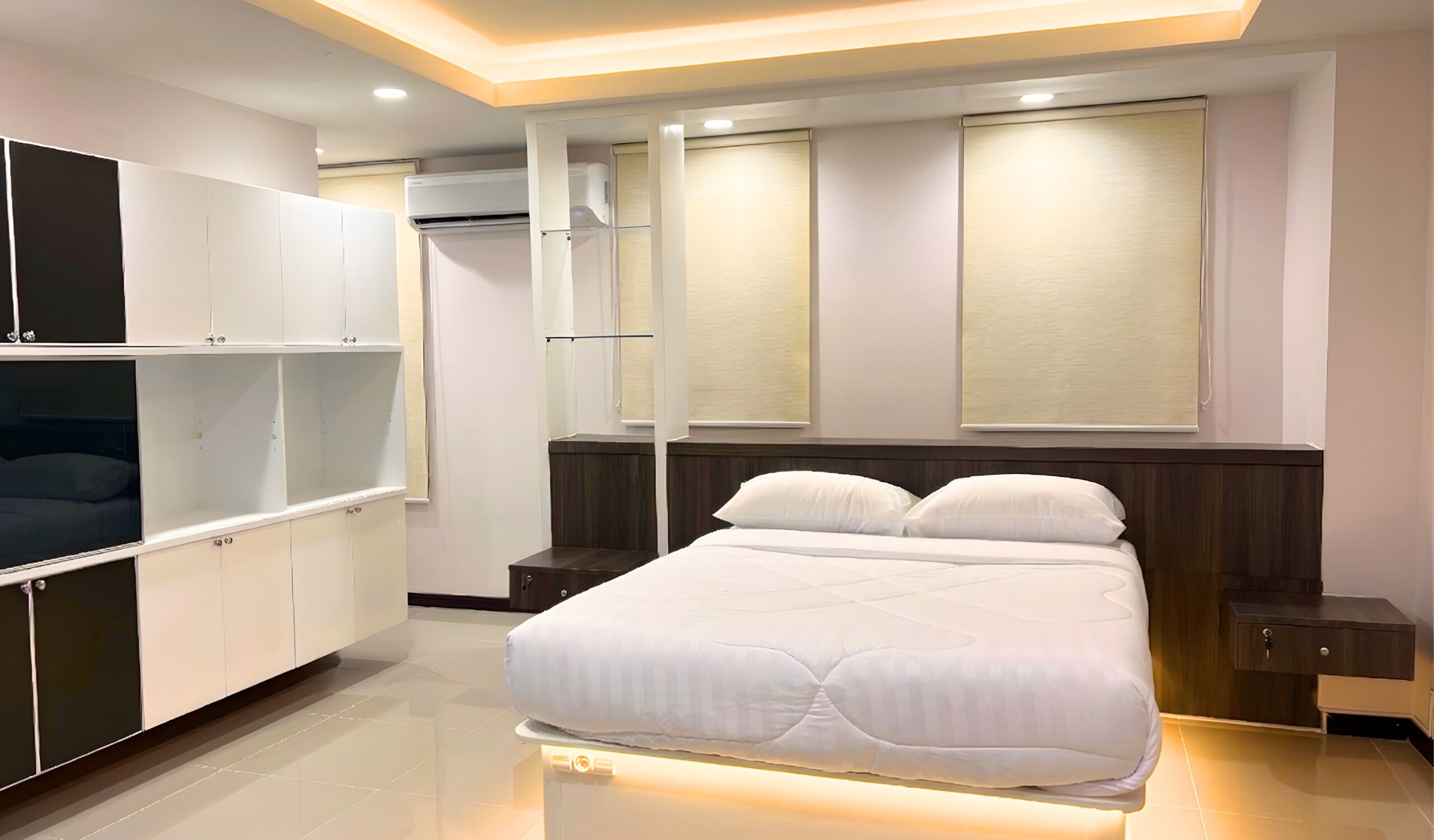A modern bedroom with a bed, built-in wardrobe, and an air conditioning unit.