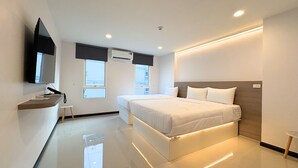 Una camera d'albergo moderna con un letto, un comodino, una TV, finestre e un condizionatore d'aria.