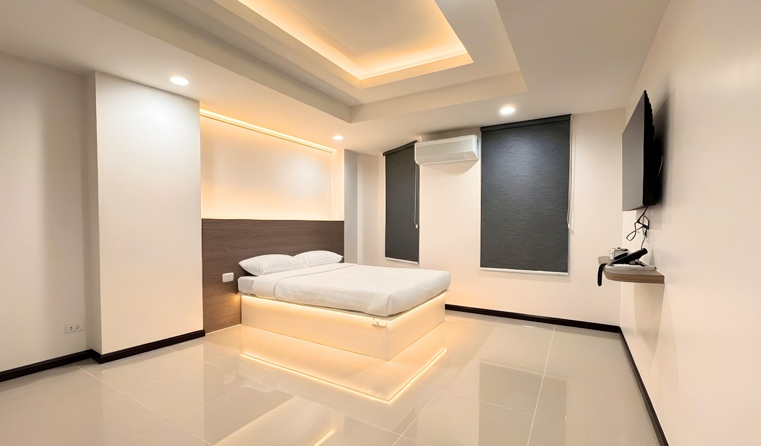 A modern bedroom with a bed, a TV, and a window.