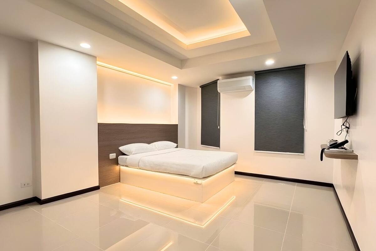 A modern bedroom with a bed, a TV, and a window.