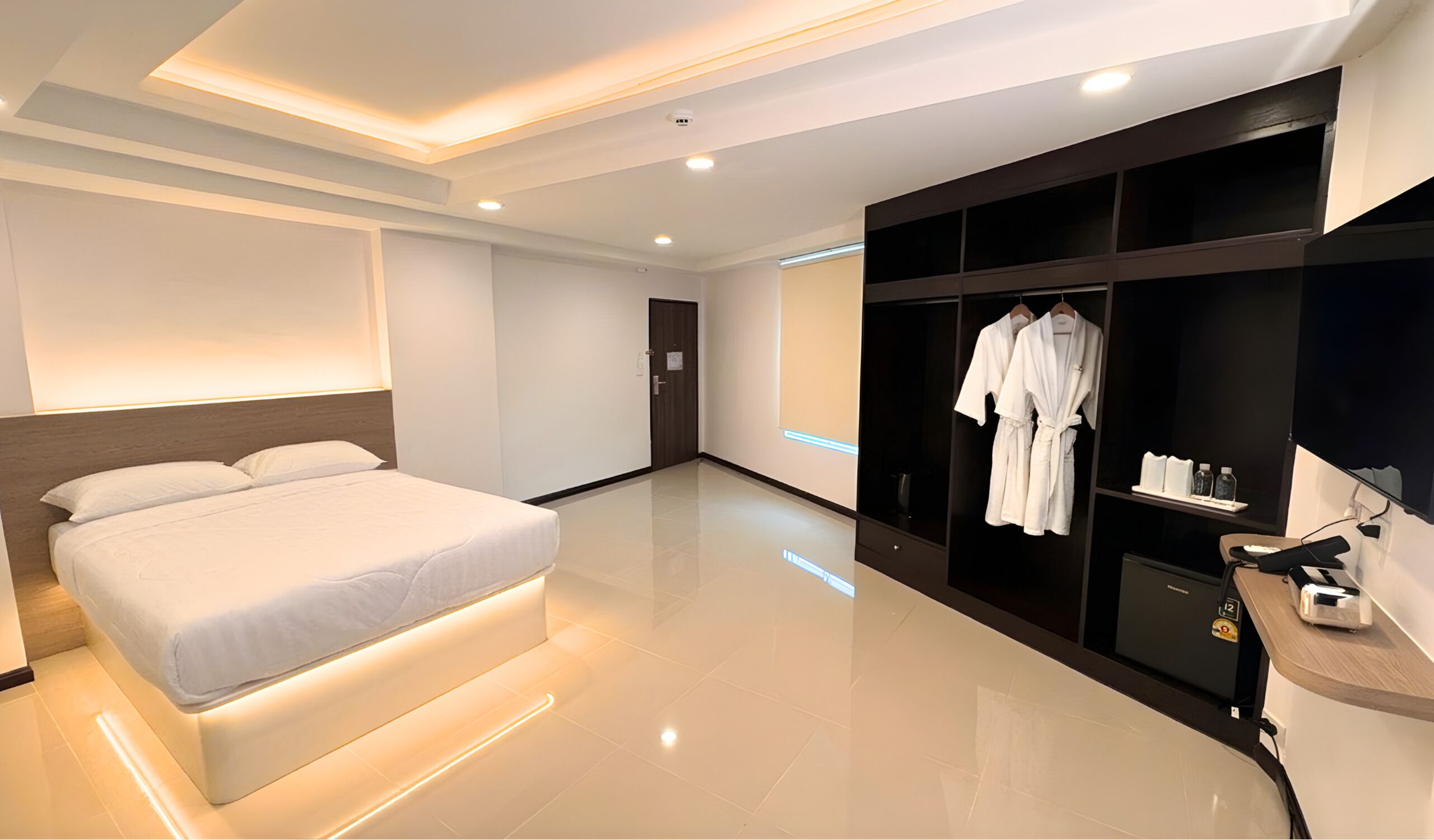 A modern hotel room with a large bed, a walk-in closet, and a bathroom with a shower and toilet.