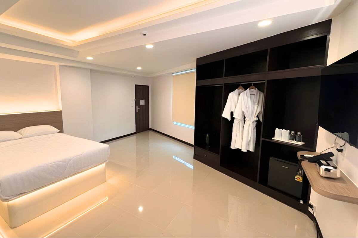 A modern hotel room with a large bed, a walk-in closet, and a bathroom with a shower and toilet.