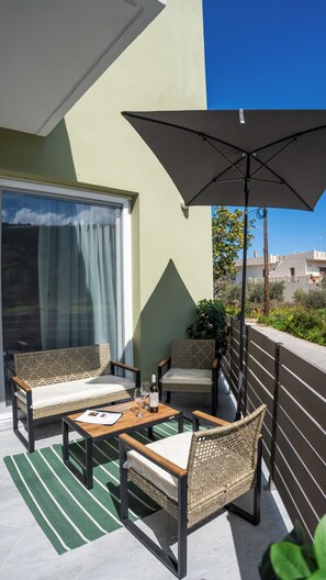 A balcony with wicker furniture, a table, and an umbrella. - Thyme Aroma - Quiet Nature Patio (Gonia, Rethymno Crete)