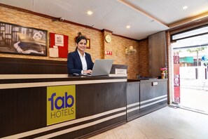 A hotel reception desk with a laptop, a clock, and a 'fab hotels' sign. - Fabhotel Step Inn Stays (Kolkata)