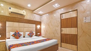 Une chambre d’hôtel comprenant un lit, des tables de chevet, un appareil de climatisation, une porte en bois et un mur en marbre.