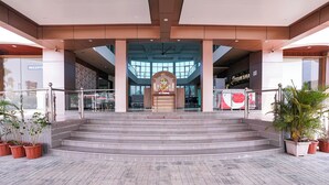 A hotel entrance with a reception desk, a staircase leading to the upper floor, and potted plants. - Fabhotel Prime Shree Palace (Palghar)
