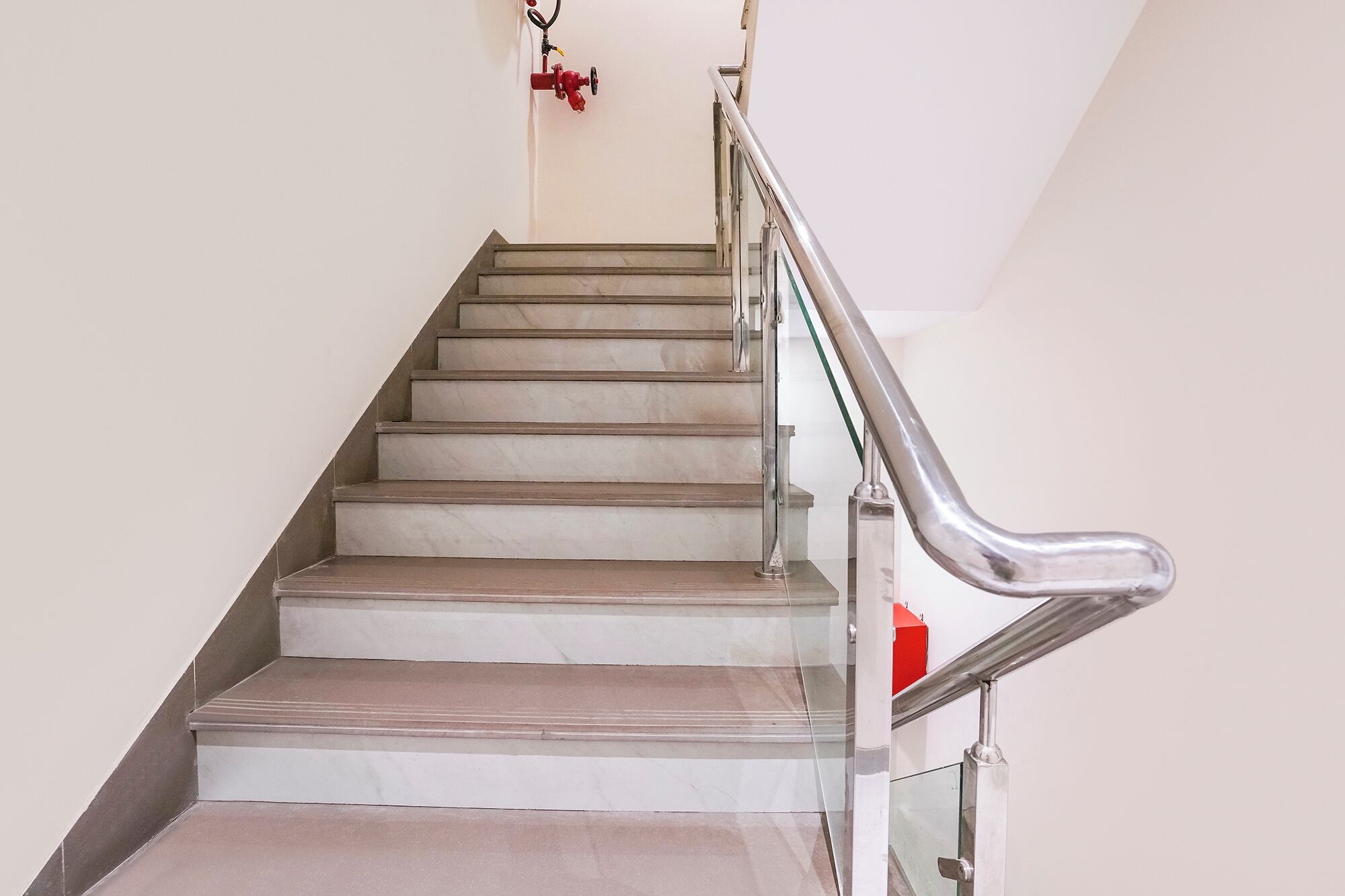 A staircase with a metal handrail and a fire hydrant mounted on the wall.
