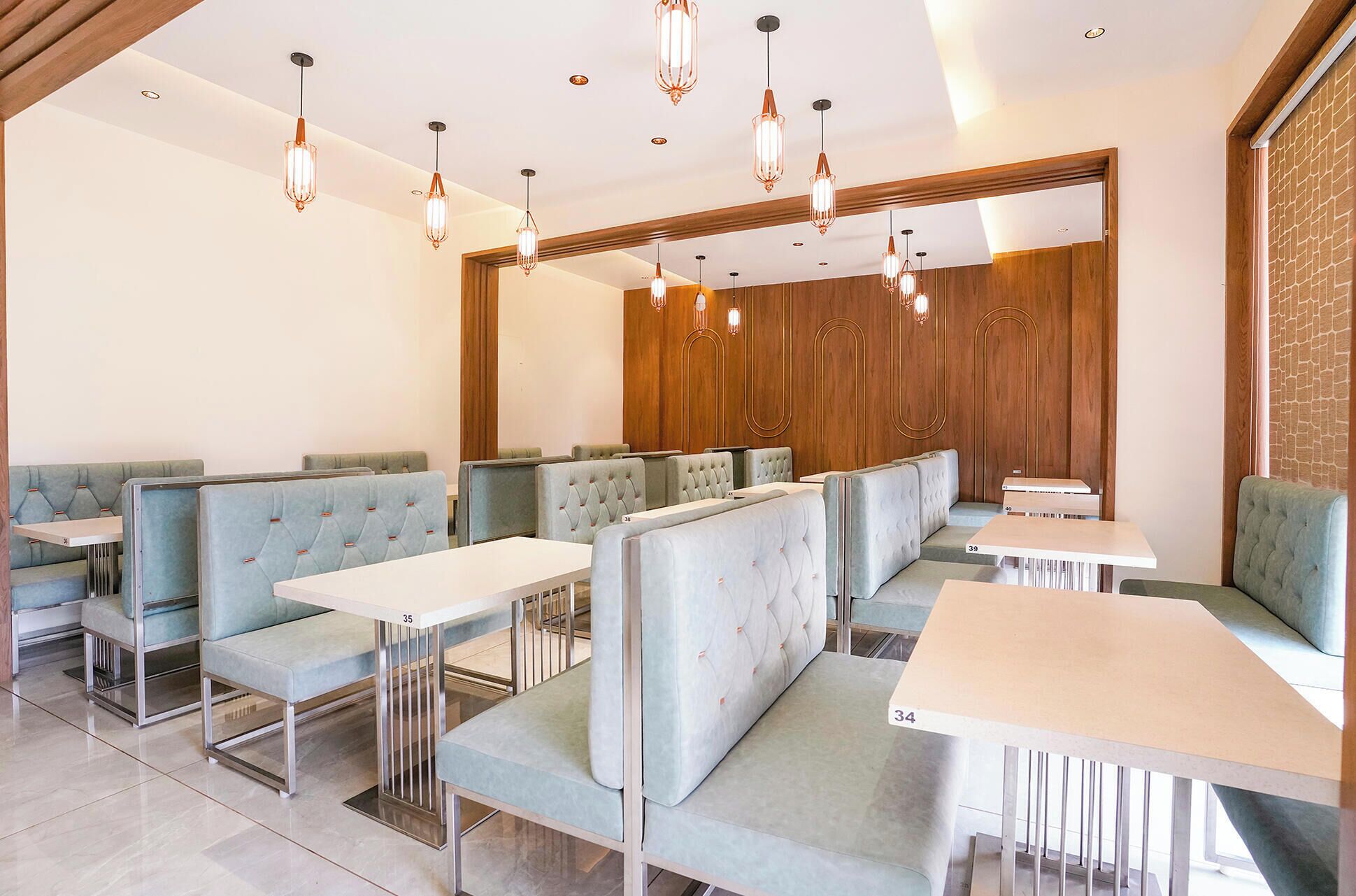 Un restaurant amb seients a boxes i taules, panells de fusta a la paret de fons i llums penjants.
