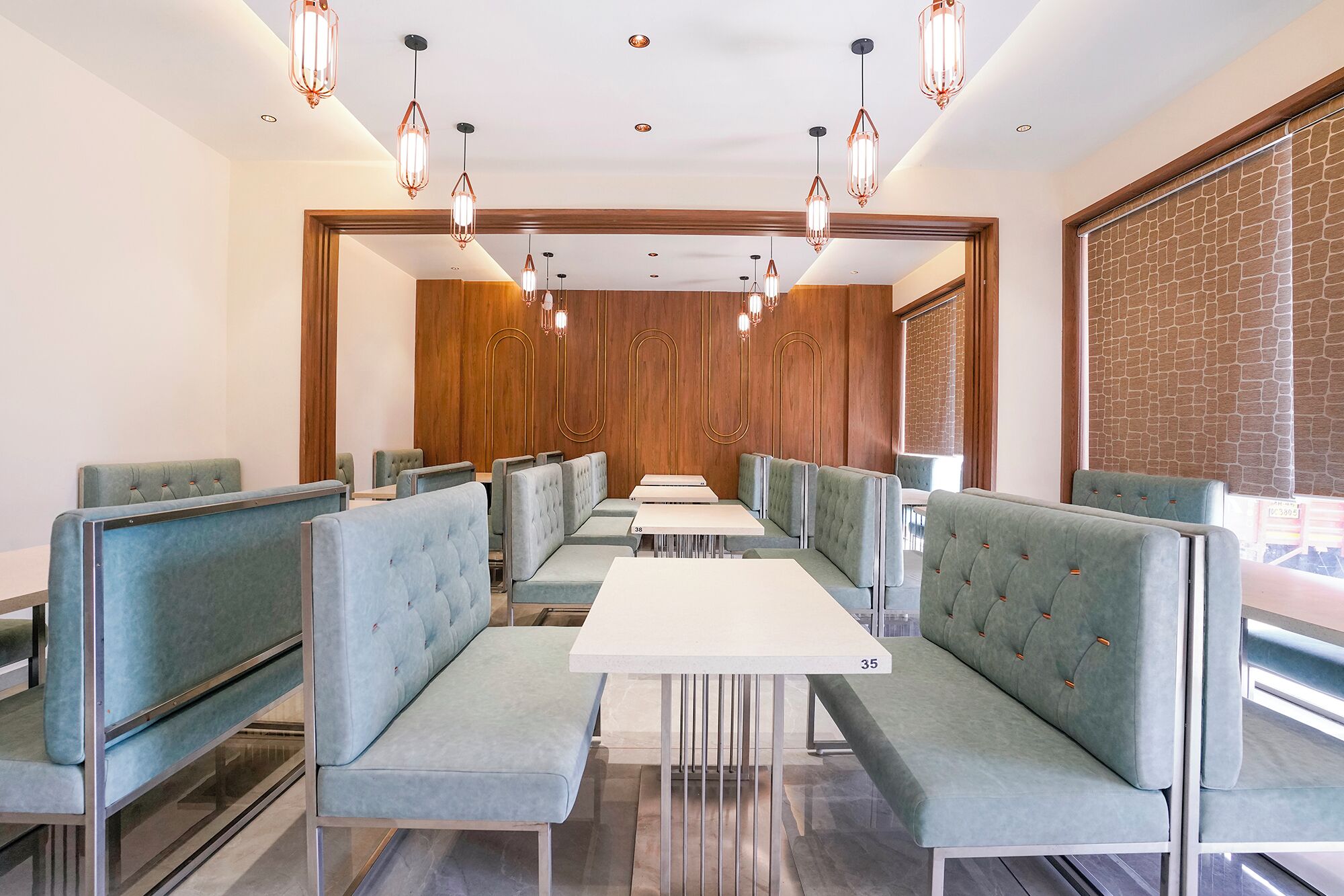 A restaurant with booths and tables, wooden paneling, and hanging pendant lights.